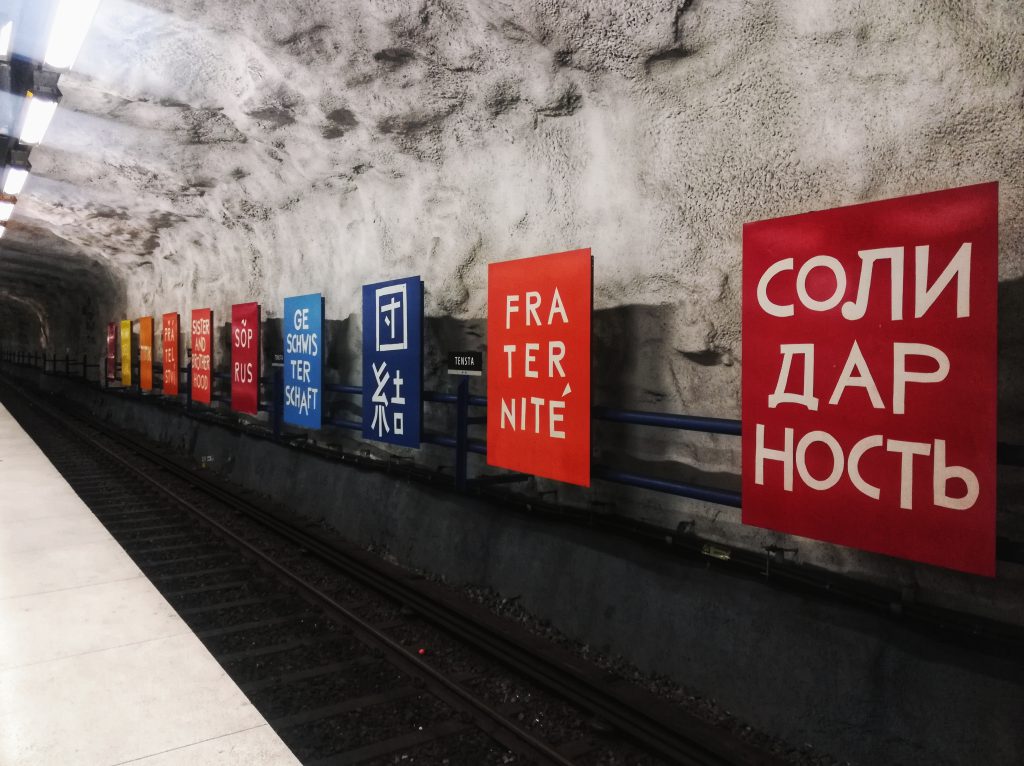 A photo of posters saying 'solidarity' and 'fraternity' in various languages, taken in Tensta subway station in Stockholm in 2020.